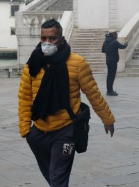 Muž s ochranou maskou prochází ulicemi Benátek