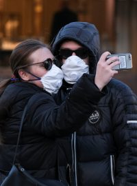 Pár, který se chrání respirátory před nákazou novým koronavirem, se fotí na Rudém náměstí v Moskvě