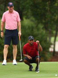 Tiger Woods (v pokleku) během golfové exhibice na Floridě se svým spoluhráčem Peytonem Manningem