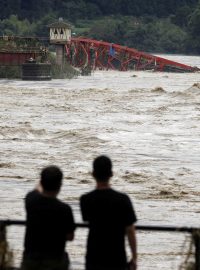 Lidé sledují řeku Kumu po prudkých deštích v prefektuře Kumamoto.