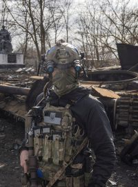 Ukrajinský voják před vrakem ruského tanku na předměstí Kyjeva