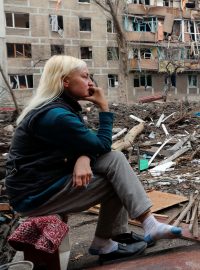 Lidé sedí před zničenými domy v Mariupolu