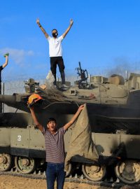 Palestinci oslavují hořící izraelské vojenské vozidlo zasažené palestinskými ozbrojenci, kteří pronikli do oblastí jižního Izraele