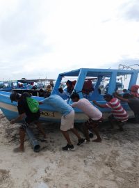 Lidé v mexickém Cancúnu vytahují před příchodem hurikánu Milton turistickou loď z vody (7. října 2024)