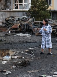 Obyvatelka stojí vedle zničených aut a poškozeného domu po útoku ruských dronů na Oděsu (fotografie z 9. listopadu 2024)