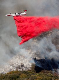 Hasiči letecky shazují růžovou směs vody, hnojiva a barvy