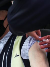 Senior v jednom z očkovacích středisek v Británii, kde lidé dostanou vakcínu a nemusí vystoupit z auta