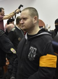 Obviněný Miroslav Marček přichází v doprovodu stráže do jednací síně.