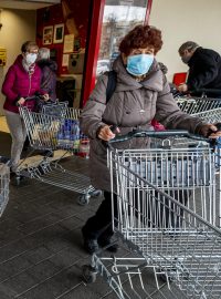 Zákazníci s očíslovanými nákupními vozíky 18. listopadu 2020 u vchodu do hypermarketu v Ústí nad Labem.