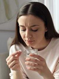 Žena s potratovou pilulkou a sklenicí vody (ilustrační foto)