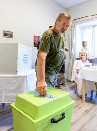 Muž hlasuje první den voleb do zastupitelstva Ústeckého kraje v Dolním Žlebu, kam je rozvodněnou řekou Labe zaplavená silnice a jediná možná cesta je vlakem