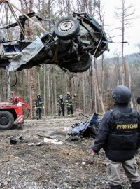 Policisté za pomoci hasičů odstraňují zničený automobil z vrbětického areálu